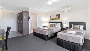 A hotel room with two beds, a desk, and a wardrobe.
