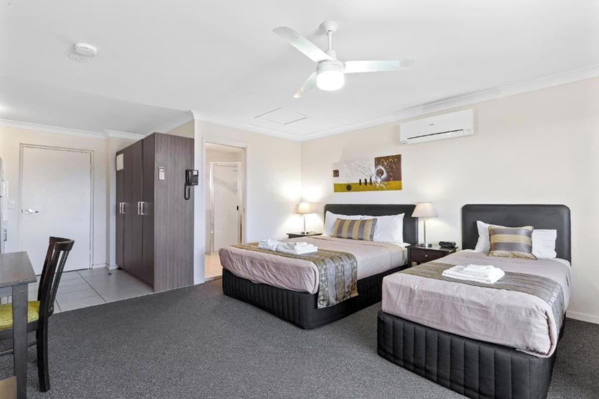 Une chambre d’hôtel avec deux lits, un bureau et une armoire.