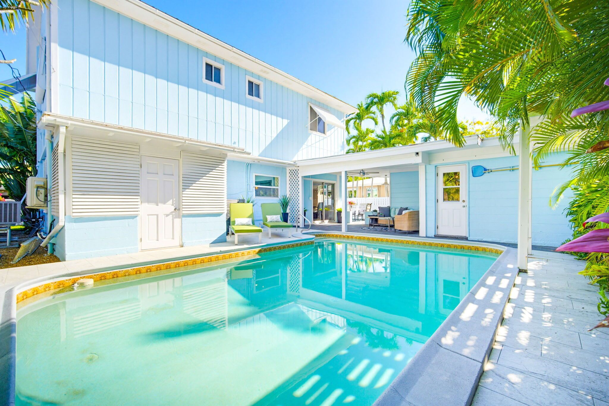 A poolside area with a pool, a covered seating area, and a building with a garage.