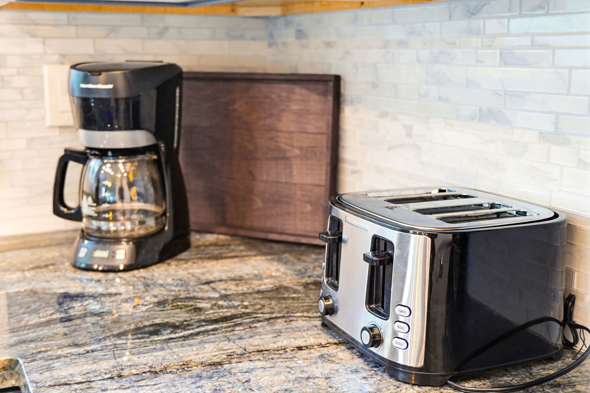 A kitchen with a coffee maker and a toaster on a granite countertop.