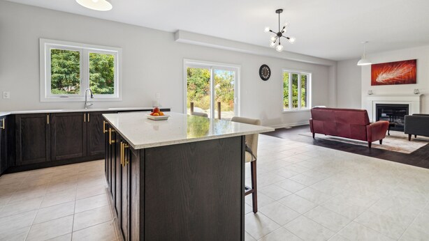 Una cocina amplia con armarios oscuros, una isla grande y un comedor con un sofá rojo.