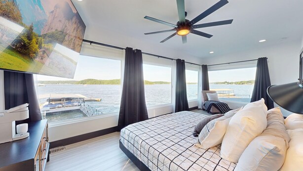 A bedroom with a large bed, a ceiling fan, and a view of a lake. - Grandview Luxe Retreat - Gravois Arm (Gravois Mills)
