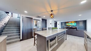 A modern kitchen with a central island, a dining area with a sofa, and a staircase. - Grandview Luxe Retreat - Gravois Arm (Gravois Mills)