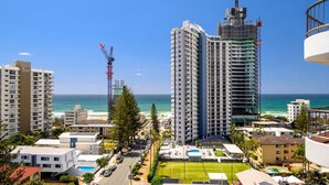 A high-rise hotel with multiple floors, a view of the ocean, and a construction crane in the background.