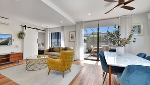 A modern living room with a sofa, yellow armchair, and a dining area with a table and chairs.