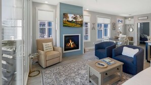 A living room with a fireplace, a sofa, a chair, and a dining area with a table and chairs.