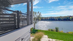 A view from a window overlooking a lake, with a grassy area and trees in the foreground.