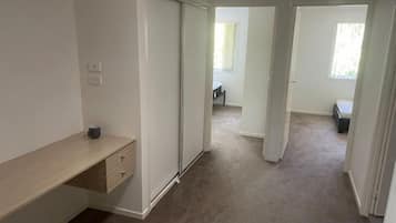 A hallway with a sliding door, a desk with drawers, and a carpeted floor.