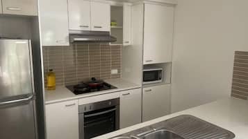 A modern kitchen with stainless steel appliances, white cabinetry, and a tiled backsplash.