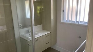 A bathroom with a glass shower enclosure, a white sink, and a window with vertical blinds. - Nice (Kuraby)