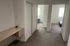 Ein Flur mit einer Schiebetür, einem Schreibtisch mit Schubladen und einem Teppichboden.