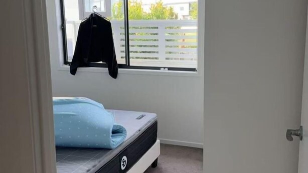 A bedroom with a bed, a window with a view of a fence, and a hanging jacket. - Nice (Kuraby)