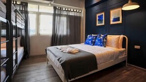 Ein Zimmer mit einem Etagenbett, einem Einzelbett, einem Fenster mit Vorhängen und einer Wand-Klimaanlage.