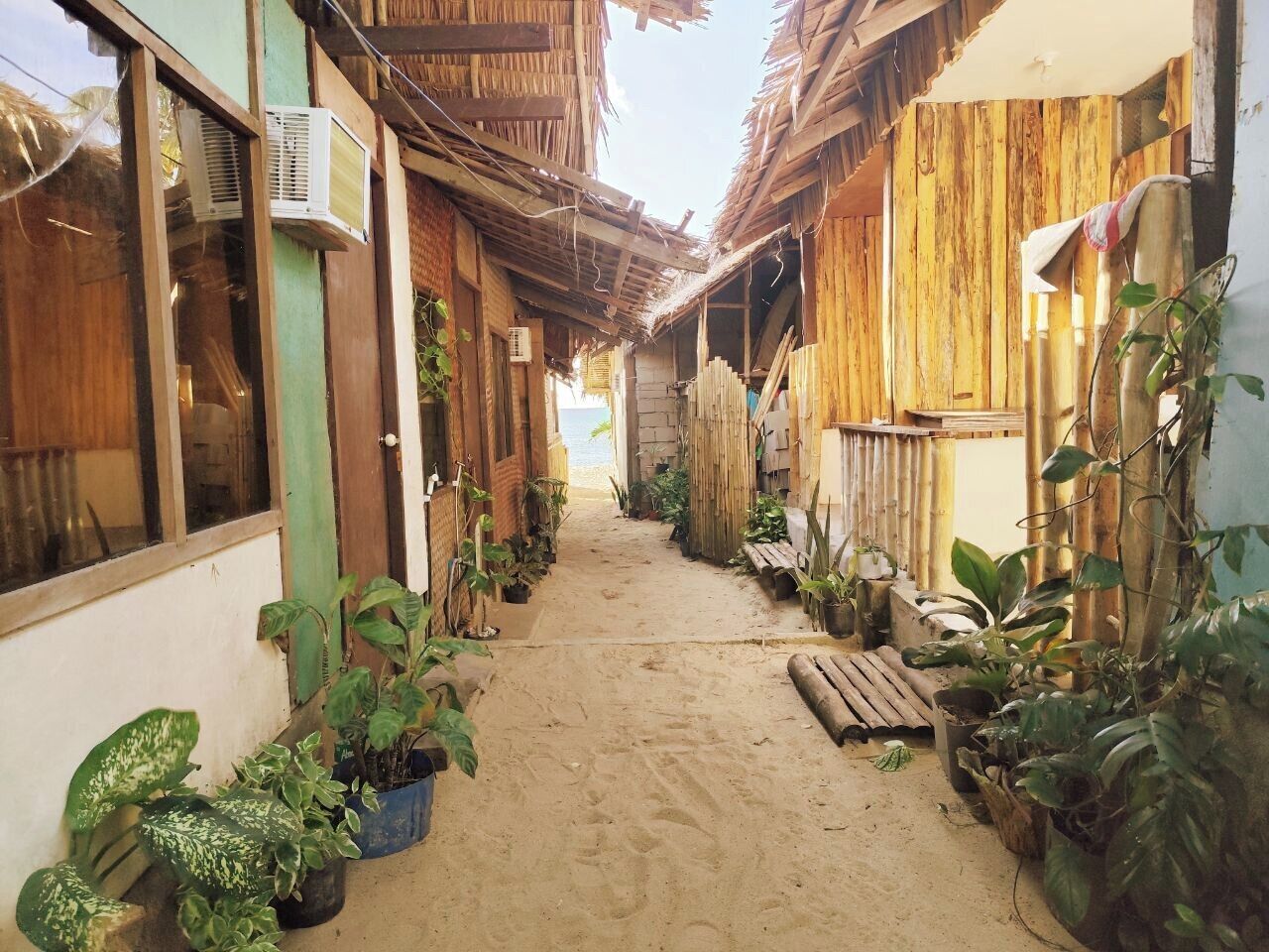 Un estrecho callejón con estructuras de madera y plantas en macetas.