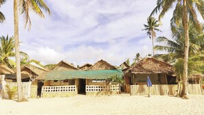 Um resort à beira-mar com cabanas de telhado de palha, palmeiras e areia.