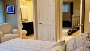 A bedroom with a large bed, a dresser, a mirror, and a door leading to a bathroom.