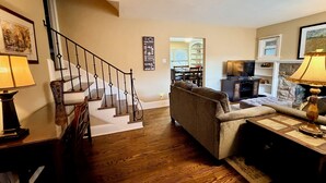 A living room with a staircase, a sofa, a coffee table, and a lamp.