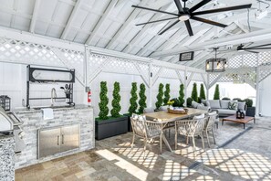 Un patio al aire libre con una encimera de piedra, una parrilla y un área de estar con mesa y sillas.