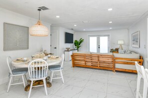 Amplia sala de estar con una mesa de comedor, sillas, un sofá y un banco de madera.