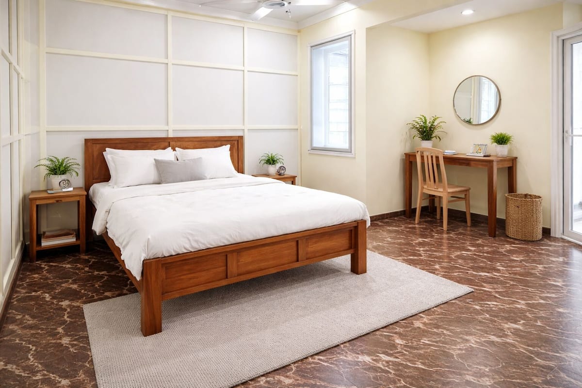 Un dormitorio con cama de madera, un escritorio, una silla, un espejo y dos plantas en macetas.