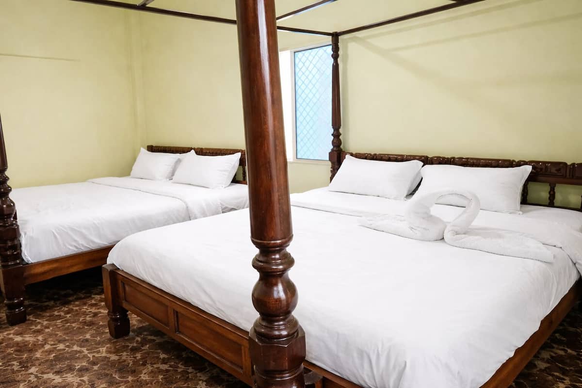 Una cama con dosel con sábanas blancas y una toalla dispuesta con arte sobre la cama.