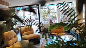 Una sala de estar moderna con sofás, una mesa de centro y vistas a la calle a través de amplios ventanales.