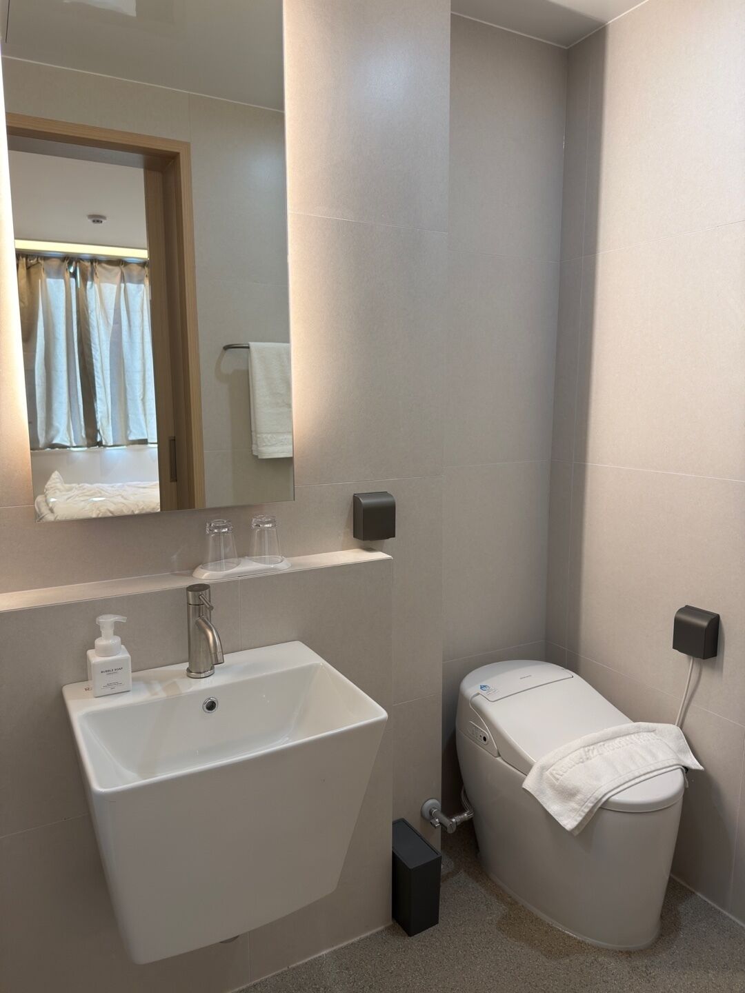 A bathroom with a white sink, mirror, and toilet.