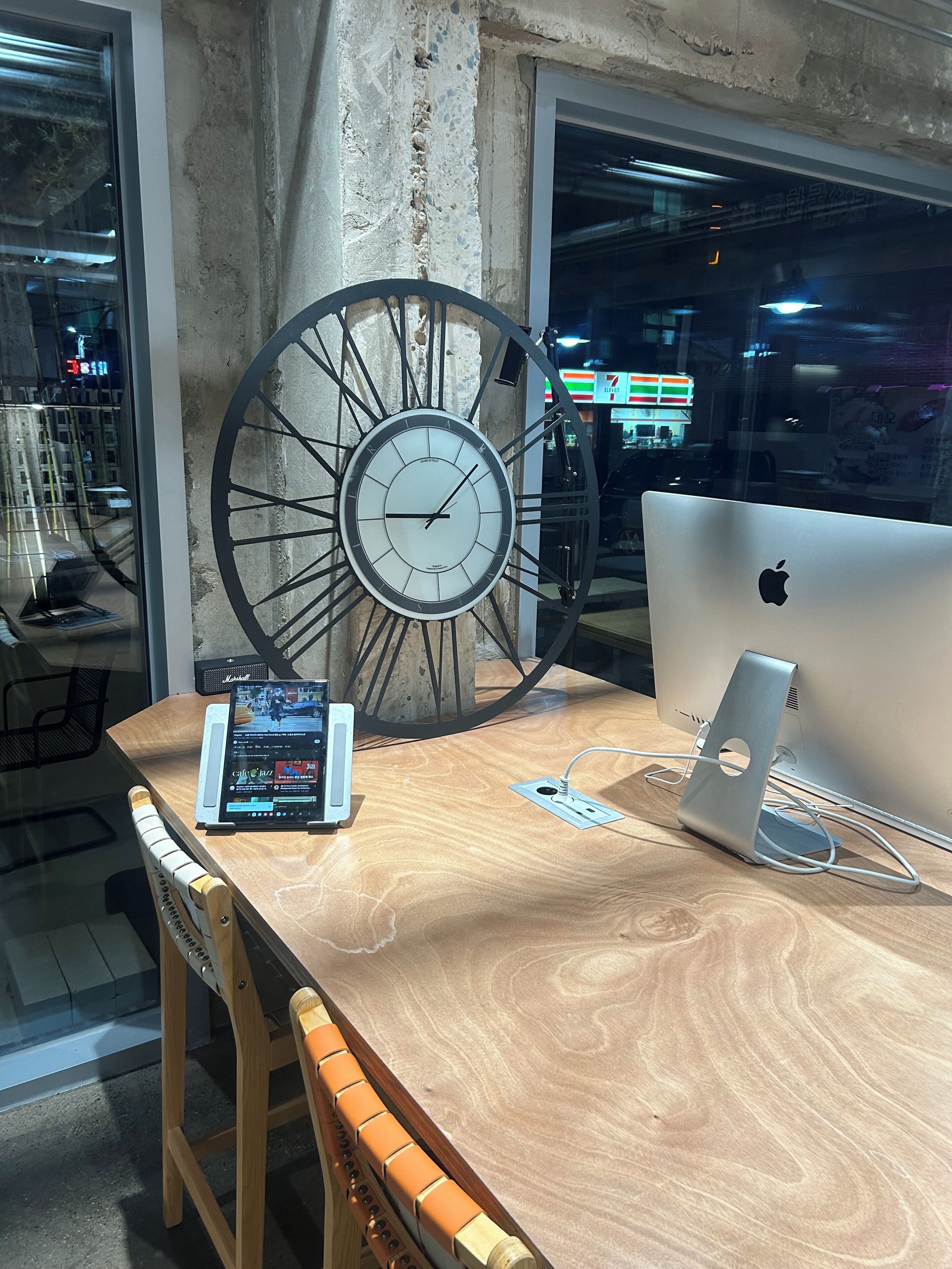 Ein Holztisch mit einem Apple iMac, einer Uhr und einem Tablet.