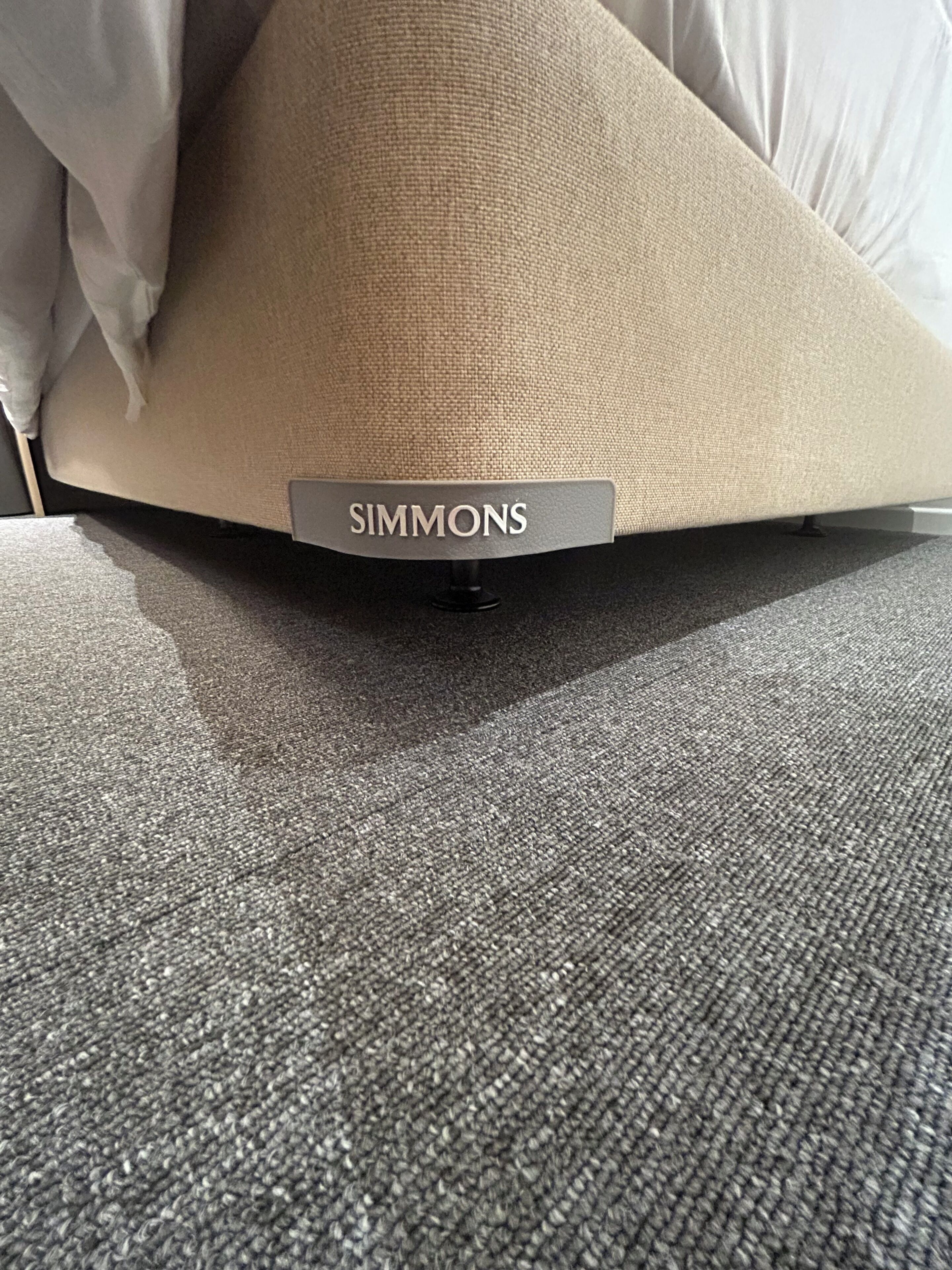 Un canapé avec un coussin portant l’inscription « SIMMONS » et un tapis gris.