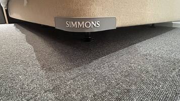 Un canapé avec un coussin portant l’inscription « SIMMONS » et un tapis gris.