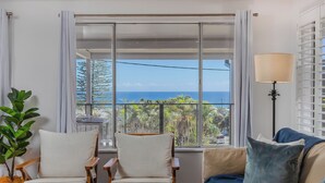 Une pièce avec vue sur l’océan, comprenant deux fauteuils, un canapé et un lampadaire.