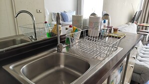 A modern kitchen with a stainless steel sink, a dish rack, and a dining area with a table and chairs. - Un bombón en Santiago Centro (Santiago)