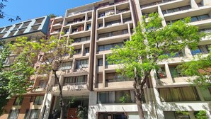 A multi-story residential building with balconies, a gated entrance, and parked cars. - Un bombón en Santiago Centro (Santiago)