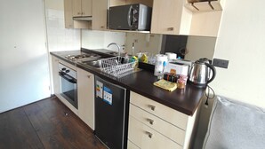 A compact kitchen with a microwave, sink, and a dish rack. - Un bombón en Santiago Centro (Santiago)