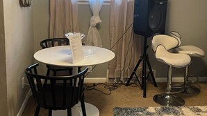 A small dining area with a round table, two chairs, a speaker, and a bar stool. - Delightful 2-bedroom house with AC in Berkeley Iconixx Getaway STL (Berkeley)