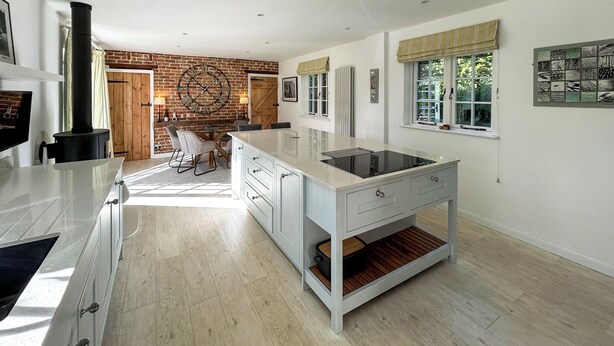 Una cocina moderna con una isla grande, suelo de madera y una pared de ladrillo decorativa.