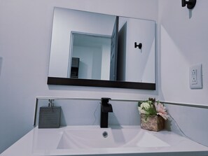 A bathroom with a white sink, a mirror, and a towel rack.