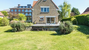 A two-story house with a sloped roof, a visible balcony, and a well-maintained lawn.