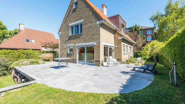 A two-story house with a stone facade and a tiled roof.
