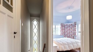 A bedroom with a large bed, a window with a diamond pattern, and a ceiling light. - Charming villa located by the dunes (Koksijde)