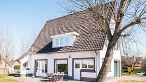 A two-story house with a tiled roof, a front porch with a table and chairs, and a green door. - Authentic coastal villa with quiet location (Koksijde)