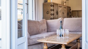 A living room with a beige sofa, a wooden coffee table with champagne glasses, and a cabinet in the background. - Authentic coastal villa with quiet location (Koksijde)