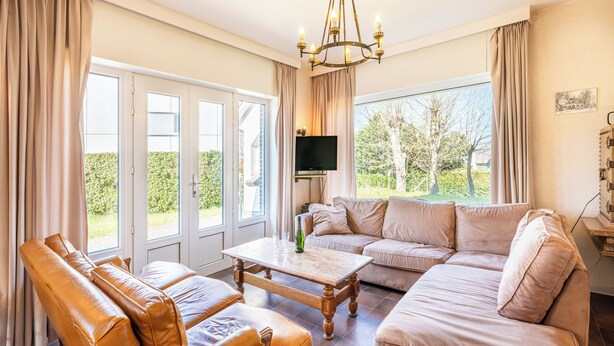 A spacious living room with a sofa, a coffee table, and a television. - Authentic coastal villa with quiet location (Koksijde)