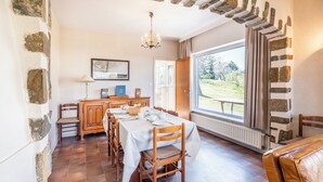 A dining area with a stone archway, wooden furniture, and a view of the outdoors. - Authentic coastal villa with quiet location (Koksijde)