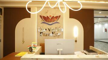 Un mostrador de recepción con una computadora Lenovo, un cartel enmarcado que dice 'The Vatik Paradise' y una pequeña bandera india.