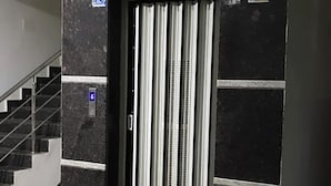 Een moderne lift met een metalen afwerking, een bedieningspaneel en een verticale ventilatie rooster.