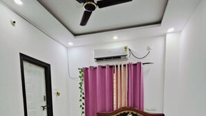 A bedroom with a bed, a ceiling fan, an air conditioning unit, and a door. - Borcelle Homes:An Essence of Luxury ✨ (Hyderabad)