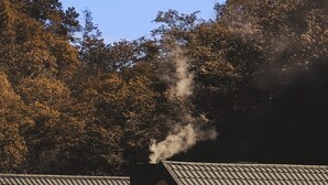 Ein Gebäude mit einem geneigten Dach und einem Schornstein, aus dem Rauch aufsteigt.