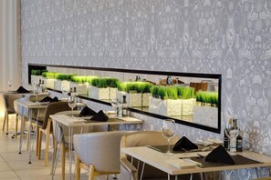 L’intérieur d’un restaurant, avec de longues tables, des chaises et un grand écran fixé au mur.