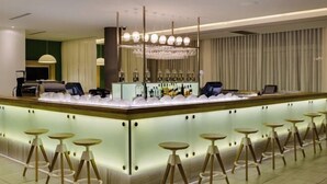 Un espace bar avec un comptoir, de nombreux tabourets et un mur recouvert de miroirs.